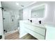 Bathroom featuring double sink vanity, updated shower, and light wood look flooring at 7909 Woodgrove Cir, Tampa, FL 33615