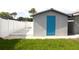 Outbuilding in a fenced yard featuring a gray exterior and a blue entry door at 7909 Woodgrove Cir, Tampa, FL 33615