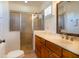 Bright bathroom featuring a glass shower and vanity with a granite countertop and wood cabinets at 831 Mandalay Ave, Clearwater, FL 33767