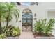 Wrought iron gate and archway leads to the home, landscaped with lush tropical plants and trees at 831 Mandalay Ave, Clearwater, FL 33767