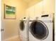 Laundry room featuring a front load washer and dryer along with white cabinets and a beach themed picture at 831 Mandalay Ave, Clearwater, FL 33767