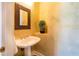 Cozy powder room features a decorative mirror, elegant pedestal sink, and leafy wallpaper, creating a serene atmosphere at 831 Mandalay Ave, Clearwater, FL 33767