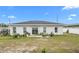 Back exterior of the home with sliding glass doors and windows overlooking a partially grassy backyard at 9429 Northcliffe Blvd, Spring Hill, FL 34606