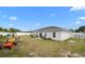 Partially grassy backyard with a white vinyl fence, small trees, and a lawn mower at 9429 Northcliffe Blvd, Spring Hill, FL 34606