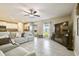 Open-concept living room with tiled floors, a modern sofa, and a kitchen with white cabinets at 9440 Lemon Drop Loop, Sun City Center, FL 33573