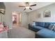 Cozy living area with a blue sectional sofa, decorative mirrors, ceiling fan, and doorway leading to another room at 9440 Lemon Drop Loop, Sun City Center, FL 33573