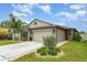 Well-maintained home with tropical landscaping, two-car garage, and sidewalk at 9514 Channing Hill Dr, Sun City Center, FL 33573