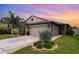 Charming single-Gathering home with well-manicured lawn, lush landscaping, and two-car garage at sunset at 9514 Channing Hill Dr, Sun City Center, FL 33573