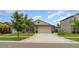 Well-maintained single-Gathering home with a manicured lawn, mature trees, and a two-car garage at 9514 Channing Hill Dr, Sun City Center, FL 33573