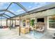 Inviting outdoor patio with stylish seating, cozy egg chair, mounted TV, and festive string lights at 9514 Channing Hill Dr, Sun City Center, FL 33573