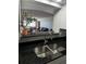 Close up of modern kitchen showcasing black granite counter, stainless sink, and open view to living area at 100 Bluff View Dr # 308A, Belleair Bluffs, FL 33770