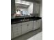 Modern kitchen with white cabinets, granite counters, and stainless dishwasher with view of living room at 100 Bluff View Dr # 308A, Belleair Bluffs, FL 33770