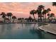 The community pool at sunset with chairs, palm trees, and waterfront views at 100 Bluff View Dr # 308A, Belleair Bluffs, FL 33770