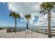 Waterfront patio with views, perfect for relaxing near the water with a table and chairs under swaying palm trees at 100 Bluff View Dr # 308A, Belleair Bluffs, FL 33770