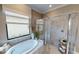 Luxurious bathroom featuring a soaking tub, a glass-enclosed shower, and elegant tile work for a spa-like experience at 10586 Buttercup Ct, Venice, FL 34293