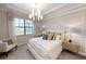 Serene bedroom featuring a queen-sized bed, a decorative chair, and plenty of natural light from a large window at 10586 Buttercup Ct, Venice, FL 34293