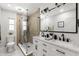 Modern bathroom featuring double sinks, marble countertops, a glass shower, and stylish black fixtures at 109 13Th St, Belleair Beach, FL 33786