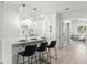 Modern white kitchen with stainless appliances, eat-in bar area, and stylish pendant lighting at 109 13Th St, Belleair Beach, FL 33786