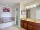 Bathroom with a double vanity, artwork, garden tub, and an open door to walk-in closet at 12121 Tree Haven Ave, Gibsonton, FL 33534