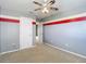 Bedroom with football fan and neutral carpet with gray walls and red stripe accent at 12121 Tree Haven Ave, Gibsonton, FL 33534