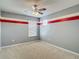 Bedroom with ceiling fan and neutral carpet with gray walls and red stripe accent at 12121 Tree Haven Ave, Gibsonton, FL 33534