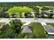 An aerial shot of the property near a baseball field, green space, and a quiet street with mature trees at 12277 Spring Hill Dr, Spring Hill, FL 34609