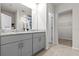 Bathroom featuring gray cabinets, double sinks with granite countertops, wood-look tile flooring, and closet at 12277 Spring Hill Dr, Spring Hill, FL 34609