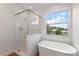 Bright bathroom features a glass shower and freestanding tub beneath a window offering a scenic view at 132 Pennsylvania Ave, Palm Harbor, FL 34683