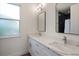 Bathroom featuring double sinks with quartz counters and modern lighting, alongside a framed mirror at 132 Pennsylvania Ave, Palm Harbor, FL 34683