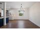Dining room with modern chandelier and hardwood flooring next to open kitchen at 132 Pennsylvania Ave, Palm Harbor, FL 34683