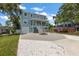 The charming two-story home is painted a delightful light blue with airy porch and stairs leading to a white driveway at 132 Pennsylvania Ave, Palm Harbor, FL 34683