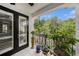 A cozy balcony area featuring black framed glass doors, potted plants, and views of the surrounding greenery at 1731 W Watrous Ave # 202, Tampa, FL 33606