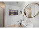 Bright white bathroom featuring a round mirror over an oval sink and decorative artwork at 1731 W Watrous Ave # 202, Tampa, FL 33606