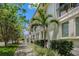 Elegant townhouse exterior featuring lush landscaping, including a mature palm tree, and a well-maintained sidewalk at 1731 W Watrous Ave # 202, Tampa, FL 33606