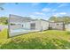 A backyard featuring a screened-in pool, green lawn, and covered carport with an AC unit at 1901 76Th N Ave, St Petersburg, FL 33702