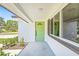 A home's green front door with decorative window and a side window, surrounded by green shrubs at 1901 76Th N Ave, St Petersburg, FL 33702