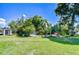 Spacious backyard with lush lawn, mature trees, landscaped areas, screened-in area, and storage shed at 2201 Horan S Way, Gulfport, FL 33707