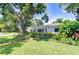 Charming single-story home boasts a lush green lawn, mature shade tree, and well-maintained landscaping at 2201 Horan S Way, Gulfport, FL 33707