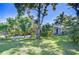 Well-maintained front yard showcases a lush lawn, mature trees, and charming single-story home at 2201 Horan S Way, Gulfport, FL 33707