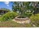 Landscaped backyard showcasing a charming stone water feature with mature trees and lush landscaping at 2221 W Lake Dr, Wimauma, FL 33598