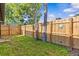 Back yard features a wooden fence, grassy lawn, and trees at 2240 Pinewood Villas Dr, Holiday, FL 34691