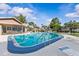 Large community pool with blue trim, surrounding chairs and landscaping at 2240 Pinewood Villas Dr, Holiday, FL 34691