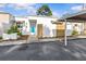 Charming home exterior features a white facade with an awning, modern wood detail, carport, and lush landscaping at 2240 Pinewood Villas Dr, Holiday, FL 34691