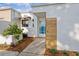 Charming home exterior features a white facade with an awning, modern wood detail, and lush landscaping at 2240 Pinewood Villas Dr, Holiday, FL 34691