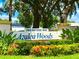 Community entrance sign, 'Azalea Woods', is surrounded by lush green plants and colorful red flowers at 2460 Northside Dr # 708, Clearwater, FL 33761