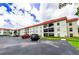 A spacious condo building with a red roof is shown with ample parking in front at 2700 Bayshore Blvd # 1206, Dunedin, FL 34698