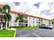 Condo building with a red roof, balconies, palm trees, and parking at 2700 Bayshore Blvd # 1206, Dunedin, FL 34698