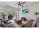 Bright living room with ceiling fan, cozy furniture, and sliding glass doors to the outdoor pool area at 27826 Sora Blvd, Wesley Chapel, FL 33544