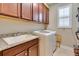 Laundry room with granite counters, sink, updated washer and dryer, and cabinet storage at 3037 Riders Pass, Odessa, FL 33556