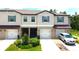 Townhouse exterior featuring a two-car garage, well-manicured landscaping, and a silver car in the driveway at 30798 Veridian Way, Wesley Chapel, FL 33543